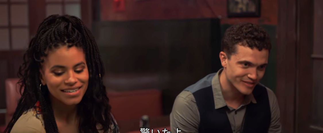 バーで笑顔を見せるアリシアとジェフリー 映画『ワウンズ:呪われたメッセージ』で、バーに並んで座り笑顔を見せるアリシアとジェフリー